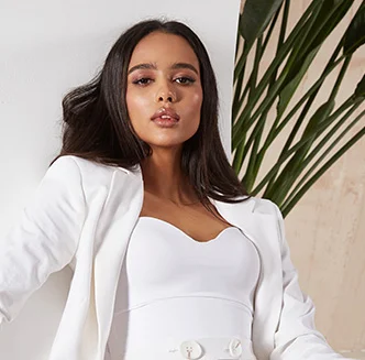 Woman with dark hair in a white blazer with plant in the backgrond - Injectables in Thiensville, WI